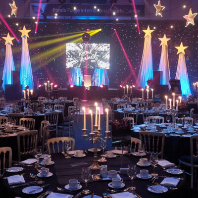 A gala dinner event with round tables set for guests to arrive and a large stage in the background.